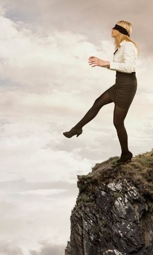 blind folded woman on edge of cliff